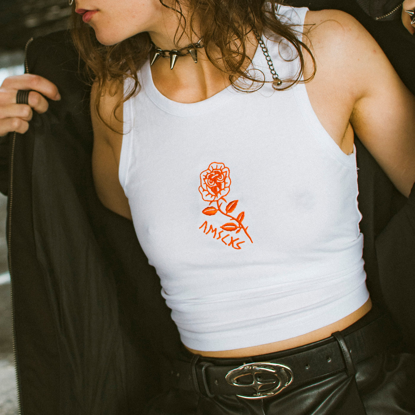 Close up of woman wearing cute white crop top with a rose illustration embroidered in the middle by american socks