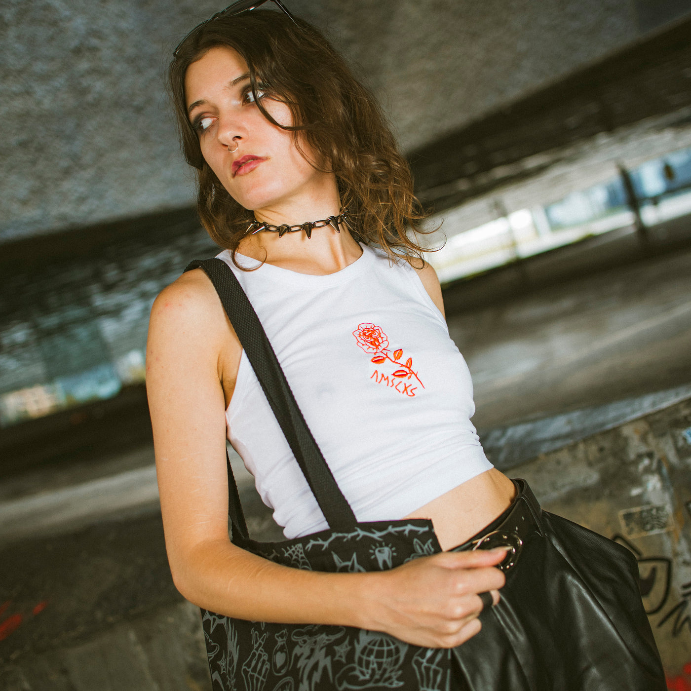 Woman posing while wearing white croptop with a rose illustration by american socks and alternative tote bag