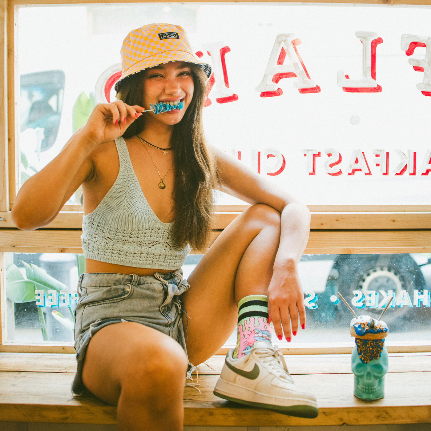 Woman eating candy wearing cool checkered bucket hat and fun cat socks american socks