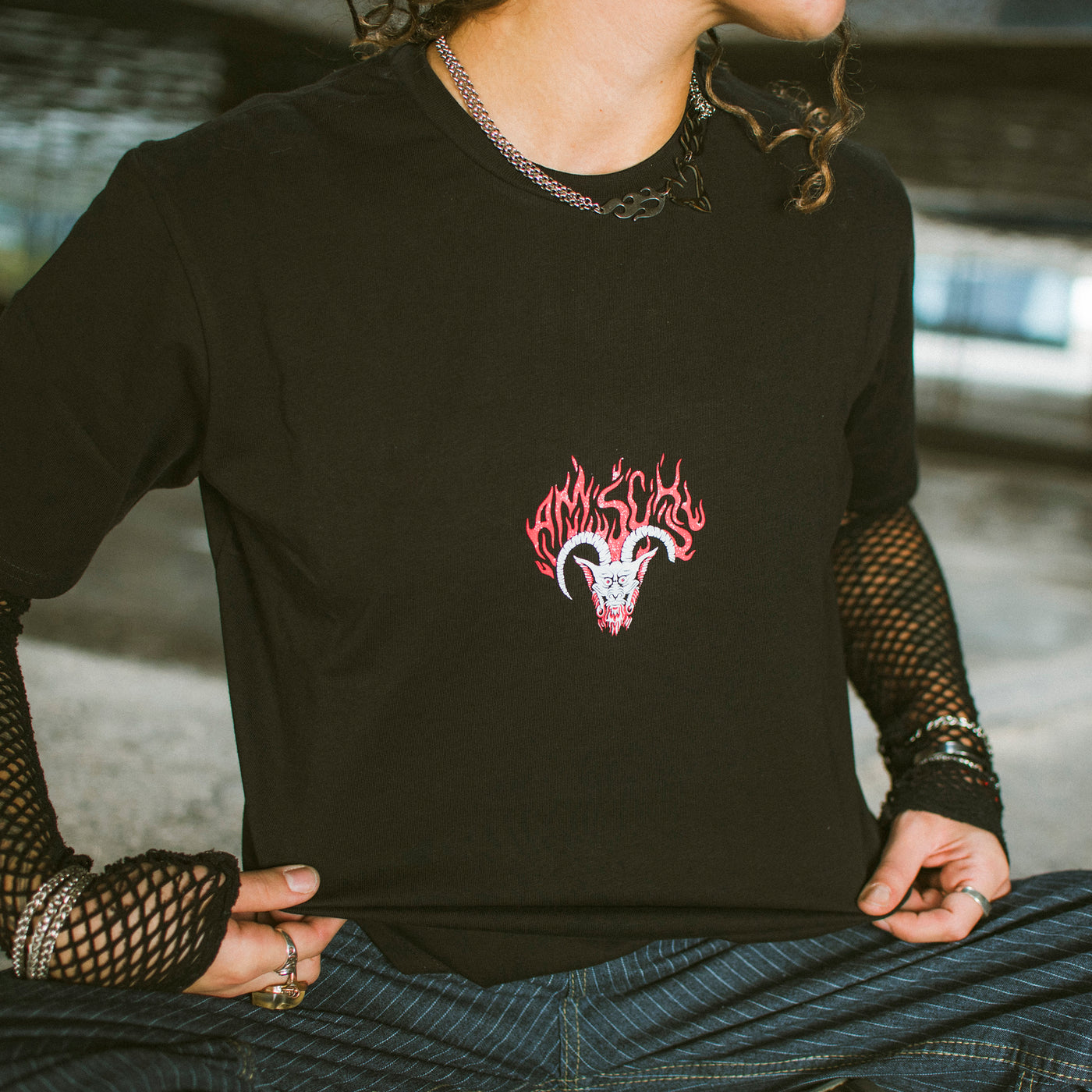 Woman showing black goth T-shirt with the face of the devil in the middle by american socks 